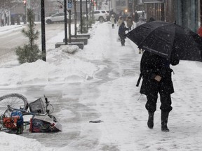 A pedestrian covers herself against the blowing snow as she walks along McGill College Ave. in 2016.