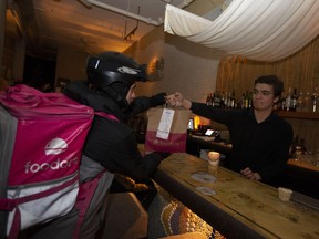 An order changes hands at the Indian restaurant Atma on St-Laurent Blvd. Foodora bases prep time on such factors as order size and time of day and week.