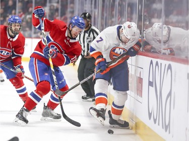 Montreal Canadiens' Philip Danault, left, and Brett Kulak watch as New York Islanders' Jordan Eberle kicks the puck away from the side boards during first period of National Hockey League game in Montreal Thursday March 21, 2019.