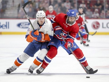 Montreal Canadiens' Philip Danault protects the puck while absorbing check from New York Islanders Mathew Barzal during first period of National Hockey League game in Montreal Thursday March 21, 2019.