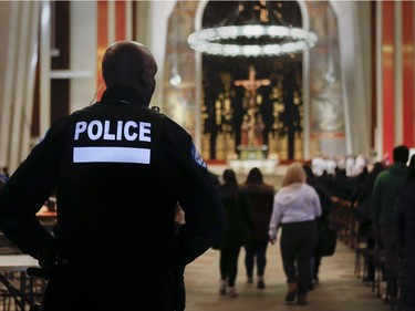 A Montreal police officer looks over people attending mass  at St Joseph's Oratory in Montreal Sunday, March 24, 2019. This is the first Sunday Mass after an attack on the rector on Friday.