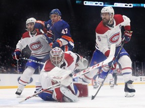 Canadiens goalie Carey Price keeps his eye on the puck, while defencemen Victor Mete, left, and Shea Weber, right, battle Islanders' Leo Komarov in front of Montreal's net Thursday night in Uniondale, N.Y.