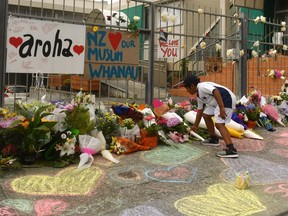 A boy places flowers outside a mosque in Kilbirnie, New Zealand, where messages of love and support poured in after after at least 49 people were killed in two mosques in Christchurch.