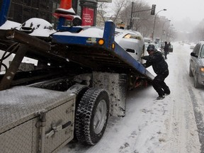 A tow truck driver removes a taxi from Atwater Ave. in Montreal on Tuesday December 29, 2015.