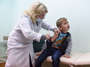 A nurse administers a measles vaccine to a young boy.