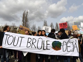 TOPSHOT - French students walk behind a banner which reads "everything is already burnt" as they take part in a march against climate change in Paris on March 8, 2019.