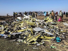 People stand near collected debris at the crash site of Ethiopia Airlines near Bishoftu, a town some 60 kilometres southeast of Addis Ababa, Ethiopia, on March 11, 2019.