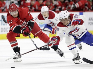 Carolina Hurricanes' Brett Pesce (22) and Montreal Canadiens' Max Domi (13) chase the puck during the second period of an NHL hockey game in Raleigh, N.C., Sunday, March 24, 2019.