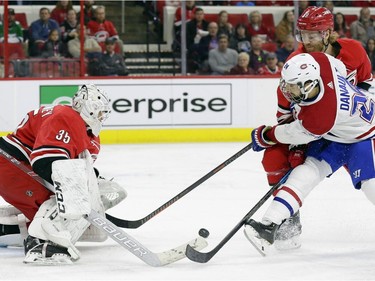 Montreal Canadiens' Phillip Danault (24) tries to score against Carolina Hurricanes goalie Curtis McElhinney (35) while Hurricanes' Dougie Hamilton (19) defends during the second period of an NHL hockey game in Raleigh, N.C., Sunday, March 24, 2019.
