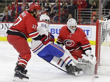 Carolina Hurricanes' Justin Faulk (27) and goalie Curtis McElhinney defend against Montreal Canadiens' Phillip Danault (24) during the first period of an NHL hockey game in Raleigh, N.C., Sunday, March 24, 2019.