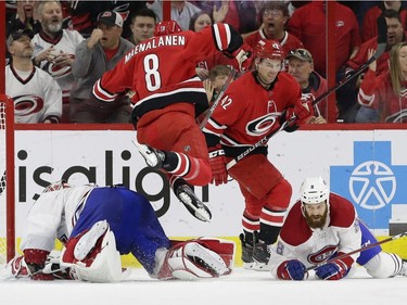 Carolina Hurricanes' Saku Maenalanen (8), of Finland, jumps over Montreal Canadiens goalie Carey Price while Hurricanes' Greg McKegg (42) looks on and Canadiens' Jordie Benn (8) falls during the first period of an NHL hockey game in Raleigh, N.C., Sunday, March 24, 2019.