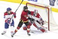 Calgary Inferno's Rebecca Leslie (centre) tries to tip the puck past Les Canadiennes de Montreal's goaltender Emerance Maschmeyer on Sunday. (The Canadian Press)