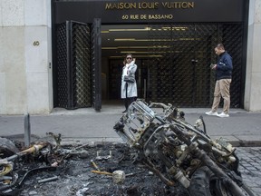 Bystanders walks past charred motorcycles on the Champs Elysees, the day after they were set on fire during the 18th straight weekend of demonstrations by the yellow vests, in Paris, France, Sunday, March 17, 2019. Paris cleaned up one of the world's most glamorous avenues Saturday after resurgent rioting by yellow vest protesters angry at President Emmanuel Macron stunned the nation.