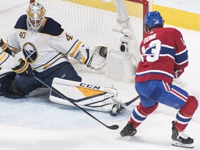 Montreal Canadiens' Max Domi (13) moves in on Buffalo Sabres goaltender Carter Hutton as Sabres' Rasmus Ristolainen defends during second period NHL hockey action in Montreal, Saturday, March 23, 2019.