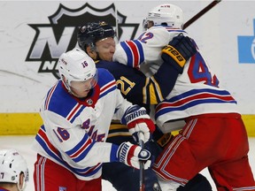 Buffalo Sabres forward Kyle Okposo (21) is hit by New York Rangers Ryan Strome (16) and Brendan Smith (42) during the third period on Feb. 15, 2019, in Buffalo. Okposo has sustained his third concussion in less than three years. The NHL Alumni Association is joining Canopy Growth in a blind study of the effects of cannabis on former players who suffer from the lingering effects of concussions.