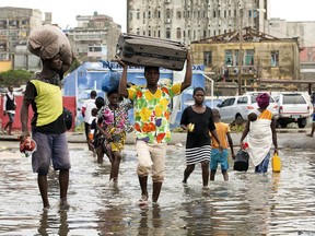 In this photo taken on Friday, March 15, 2019 and provided by the International Red Cross, people carry their personal effects after Tropical Cyclone Idai, in Beira, Mozambique. Mozambique's President Filipe Nyusi says that more than 1,000 may have by killed by Cyclone Idai, which many say is the worst in more than 20 years. Speaking to state Radio Mozambique, Nyusi said Monday, March 18 that although the official death count is currently 84, he believes the toll will be more than 1,000.