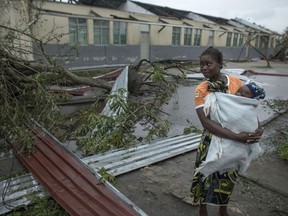 A woman makes her way to a school building being used as an emergency shelter for some 300 local people who are unable to return to their homes following cyclone force winds and heavy rain in the coastal city of Beira, Mozambique, Sunday March 17, 2019. More than 1,000 people are feared dead in Mozambique four days after a cyclone slammed into the southern African country destroying vulnerable residential areas.