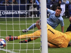 Montreal Impact goalkeeper Evan Bush reaches for the ball as Sporting Kansas City forward Krisztian Nemeth watches his shot go in the goal in the 43th minute Saturday, March 30, 2019, during an MLS match in Kansas City, Mo.