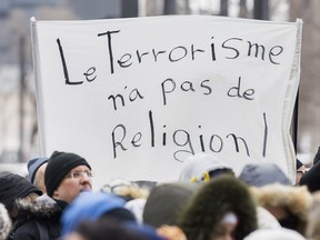 People hold up signs as they attend a vigil in Montreal, Sunday, March 17, 2019, following a shooting at a mosque in Christchurch, New Zealand which left 50 people dead and many more injured.