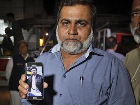 A relative shows the picture of Syed Areeb Ahmed, a Pakistani citizen who was killed the Christchurch mosque shooting, on his cell phone outside his home in Karachi, Pakistan, Saturday, March 16, 2019. Pakistan's foreign minister says at least six Pakistanis were killed in the New Zealand mosque shootings. Shah Mahmood Qureshi says authorities in Christchurch, where the shootings took place, are trying to determine whether three other Pakistanis who have been missing since Friday's attack were among the fatalities.