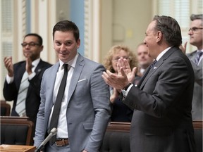 Quebec Minister of Immigration, Diversity and Inclusiveness Simon Jolin-Barrette is applauded by Quebec Premier Francois Legault, right, and members of the government after he tabled the new secularism bill.