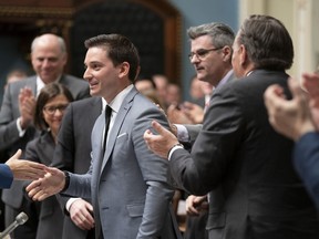 Quebec Minister of Immigration, Diversity and Inclusiveness Simon Jolin-Barrette is applauded by Quebec Premier Francois Legault, right, and members of the government after he tabled a legislation on laicity of the state, Thursday, March 28, 2019 at the legislature in Quebec City.