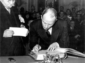 Adélard Godbout, premier of Quebec, signs the Golden Book during the ceremony in which he and his ministers took the oath of office in the Legislative Council Chamber at Quebec City on Nov. 8, 1939. At left is Alfred Morisset, clerk of the executive council.