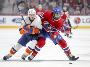Montreal Canadiens' Phillip Danault protects the puck while absorbing a check from New York Islanders' Mathew Barzal during first period in Montreal on March 21, 2019.