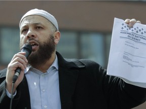 Controversial imam and activist Adil Charkaoui holds a copy of Bill 21 during Sunday's protest at Place Émilie-Gamelin.