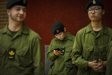 Cadet Minjae Cho checks his cellphone during a break from drill and marching at the Royal Montreal Regiment in Westmount.