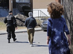 A girl watches as a police officer leads a man to talk to other police officers near a duplex on Kildare Rd. in the Côte-St-Luc Saturday. Residents reported hearing gunshots early Saturday morning. The Montreal police have made an arrest and are seeking two others.