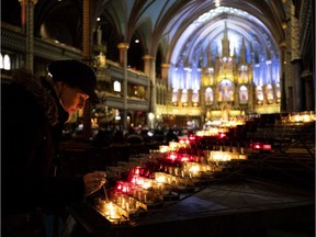 A woman lights a candle at Notre-Dame Basilica in Montreal, on Tuesday, April 16, 2019.