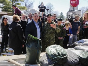 Premier François Legault looks towards the encroaching Rivière des Prairies beside a wall of sand constructed by Canadian military in the Ile Bigras area of Laval near Montreal Sunday, April 21, 2019.