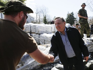 Premier François Legault shakes hands with Canadian military soldiers as they construct a wall of sand on IÎle-Bigras near Montreal on Sunday, April 21, 2019. Legault was touring areas of Laval affected by rising waters.