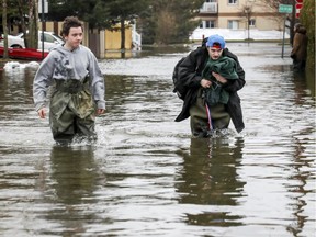 Brothers Xavier, left, and Olivier Blais wade down flooded Filion St. on their way to their grandparents' home in Lachute April 26, 2019.