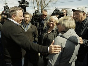 Premier François Legault reaches out to Ste-Marthe-sur-le-Lac Mayor Sonia Paulus in her community near Montreal on SUnday.