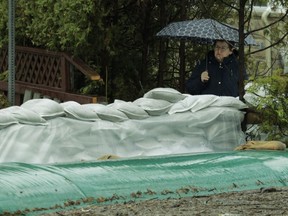 Pierrefonds resident Manon Boileau watches workers stacking sandbags near the Rivière des Prairies in the Pierrefonds area of Montreal Saturday, April 27, 2019.