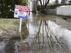 A sign is reflected in the floodwaters on 39th Ave. in Ste-Marthe-sur-le-Lac, west of Montreal, Monday April 29, 2019.