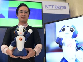 An employee, wearing a t-shirt wearable device, displays a robot called "Sota" at a booth during the launch of the Microsoft AI signature campaign study in Manila on March 21, 2019. - Sota, which weights 1kg, is designed to assist the elderly with health functions by interacting with wearable devices to check a user's blood pressure and heart rate.