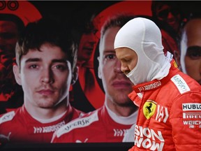 Ferrari driver Sebastian Vettel walks back to his pit garage, past a poster showing teammate Charles Leclerc, after Friday practice at Shanghai International Circuit.