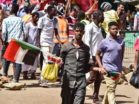 A Sudanese peddlar walks with national flags.