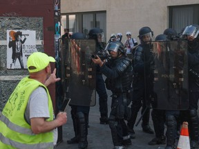 An anti-riot police officer aims with a 40-millimetre rubber defensive bullet launcher (LBD 40) as he faces a protester during an anti-government demonstration called by the 'Yellow Vests' (gilets jaunes) movement, on April 20, 2019 in Paris.