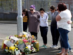 People gather around the floral tributes placed at the scene in the Creggan area of Derry (Londonderry) in Northern Ireland on April 20, 2019 where journalist Lyra McKee was fatally shot amid rioting on April 18.