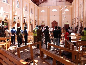 Sri Lankan security personnel walk through debris following an explosion in St Sebastian's Church in Negombo, north of the capital Colombo, on April 21, 2019. - A series of eight devastating bomb blasts ripped through high-end hotels and churches holding Easter services in Sri Lanka on April 21, killing nearly 160 people, including dozens of foreigners.