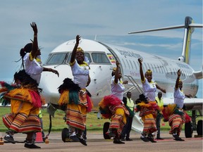 Traditional dancers perform a routine in front of a newly acquired Uganda Airlines Bombardier CRJ900 aircraft on the runway at Entebbe Airport on the outskirts of Kampala on April 23, 2019. - The first two planes purchased in a bid to relaunch Uganda Airlines have been delivered, nearly two decades after the East African country's national carrier collapsed. The two Bombardier CRJ900 jet airliners, which can carry up to 90 people, landed at the Entebbe airport outside the capital Kampala during a ceremony attended by President Yoweri Museveni.