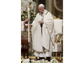 Pope Francis holds a candle as he presides over a solemn Easter vigil ceremony in St. Peter's Basilica at the Vatican, Saturday, April 21, 2019.