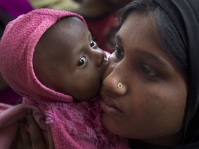 A newly arrived Rohingya refugee child licks the cheek of her mother, Azida Khatoon, 20, as they wait in a food distribution line in the Kutupalong refugee camp near Cox's Bazar, Bangladesh in 2018.