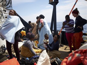 Migrants stand on the dock of the Sea-Watch rescue ship after being rescued in the waters off Libya Wednesday, April 3, 2019. The German humanitarian group Sea-Watch says the ship it operates in the central Mediterranean Sea has rescued 64 migrants in waters off Libya. Sea-Watch said those rescued from a rubber dinghy included 10 women, five children and a newborn baby.