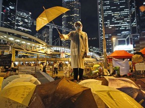 FILE - In this Oct. 9, 2014, file photo, a protester holds an umbrella during a performance on a main road in the occupied areas outside government headquarters in Hong Kong's Admiralty. A Hong Kong court has found nine leaders of 2014 pro-democracy demonstrations guilty on public nuisance and other charges.