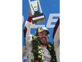 FILE - In this June 17, 2018, file photo, Fernando Alonso, of Spain, celebrates with teammates after winning the the 86th 24-hour Le Mans endurance race, in Le Mans, western France.  McLaren will put a car on track at Indianapolis Motor Speedway for the first time since 1976 when Fernando Alonso tests Wednesday. Alonso is trying to win motorsports version of the Triple Crown, while the famed manufacturer is considering a return to IndyCar competition.